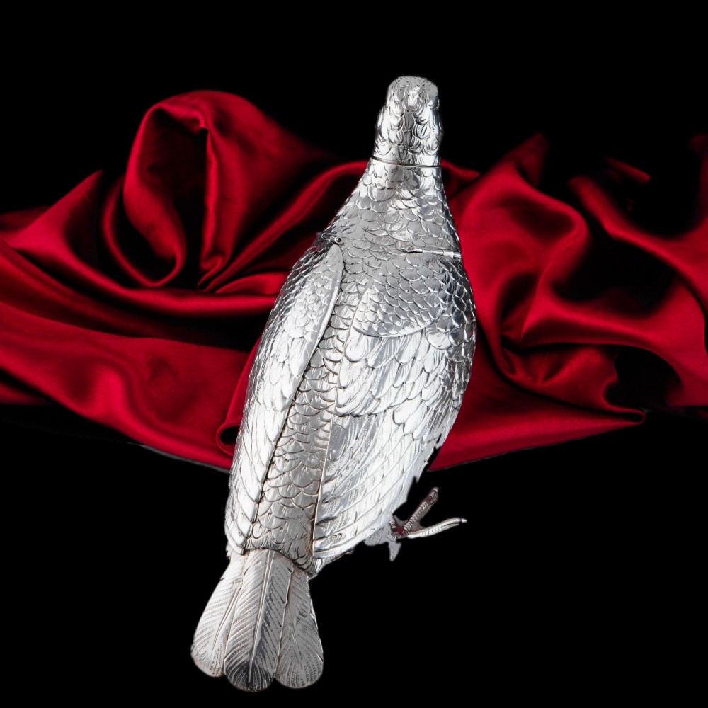 A solid silver model of a partridge with chased feather detailing standing on two feet with a hinged compartment lid along its back. View XXVIII