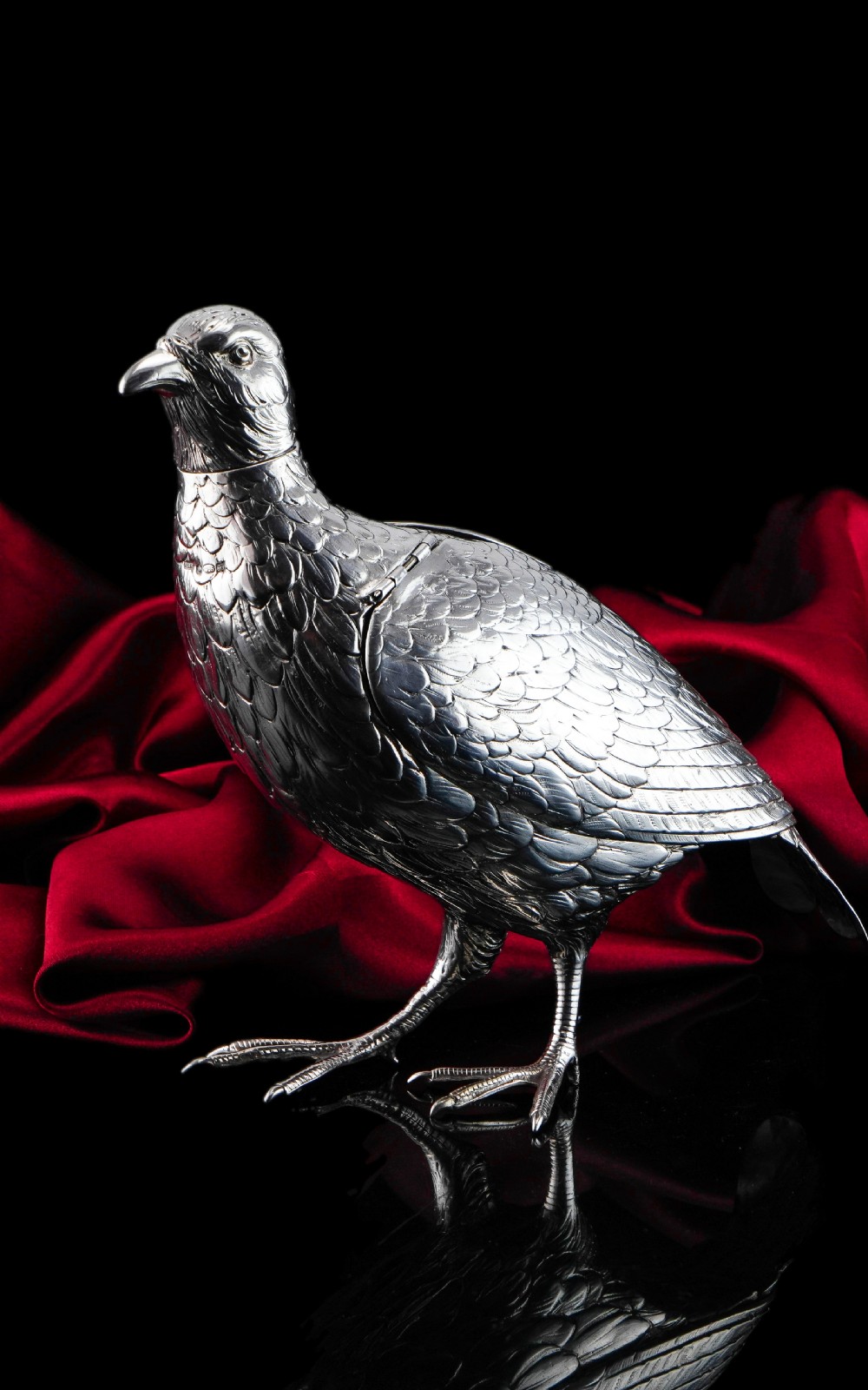 A solid silver model of a partridge with chased feather detailing standing on two feet with a hinged compartment lid along its back. View XXX