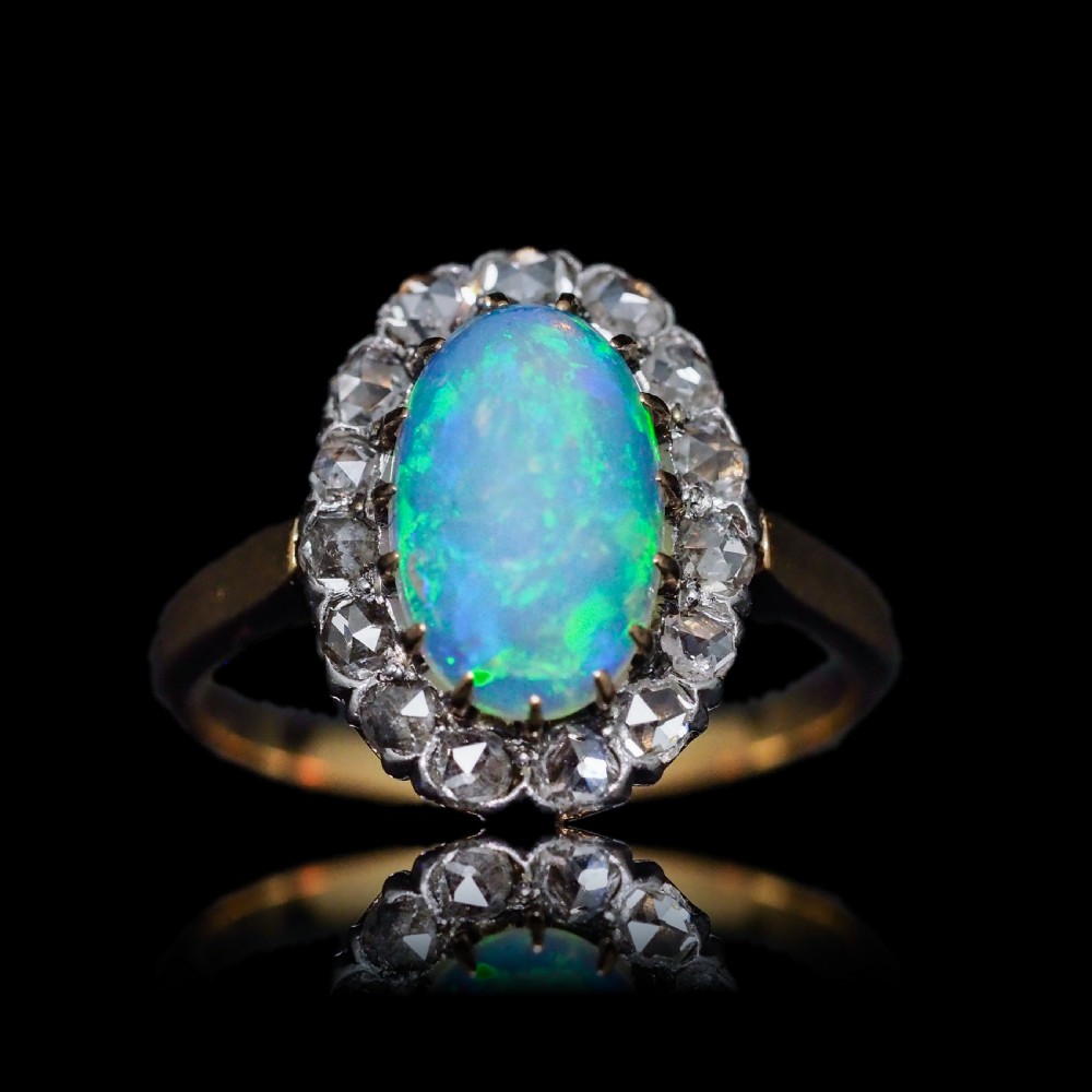 Victorian 18k gold cluster ring featuring an oval cabochon opal surrounded by a halo of rose-cut diamonds. View V