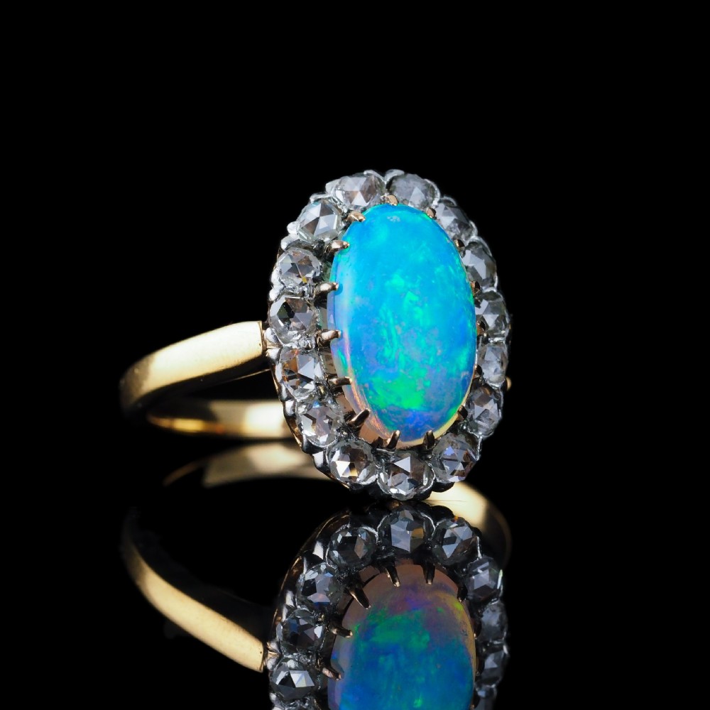 Victorian 18k gold cluster ring featuring an oval cabochon opal surrounded by a halo of rose-cut diamonds. View VI