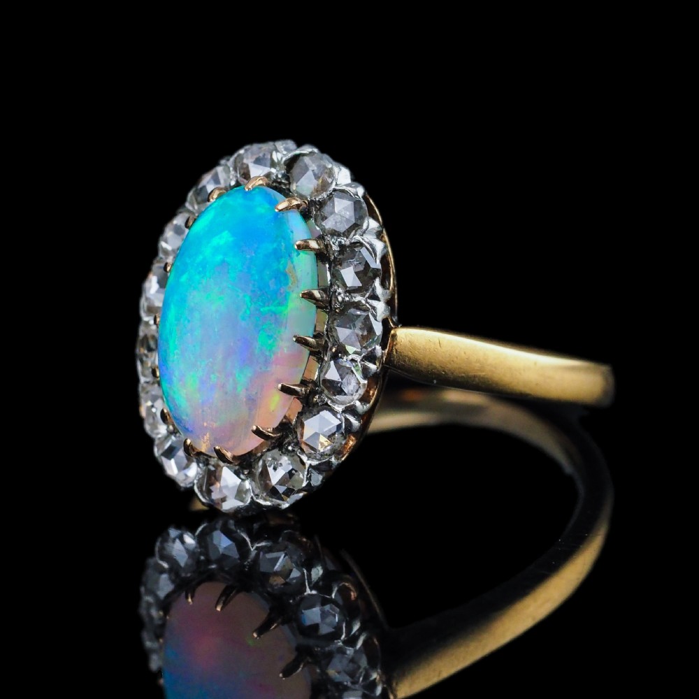Victorian 18k gold cluster ring featuring an oval cabochon opal surrounded by a halo of rose-cut diamonds. View VIII
