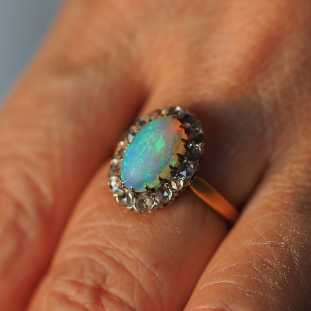 Victorian 18k gold cluster ring featuring an oval cabochon opal surrounded by a halo of rose-cut diamonds. View XII