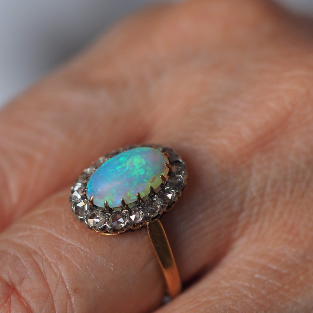 Victorian 18k gold cluster ring featuring an oval cabochon opal surrounded by a halo of rose-cut diamonds. View XIV