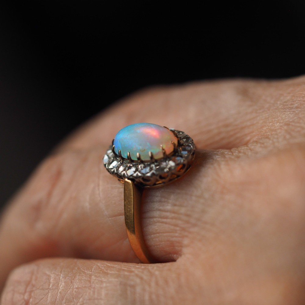 Victorian 18k gold cluster ring featuring an oval cabochon opal surrounded by a halo of rose-cut diamonds. View XV