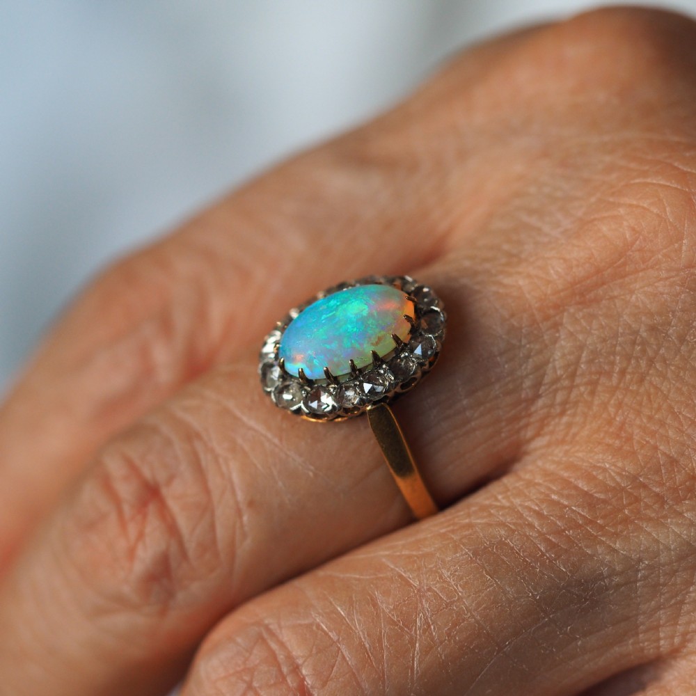 Victorian 18k gold cluster ring featuring an oval cabochon opal surrounded by a halo of rose-cut diamonds. View XVI