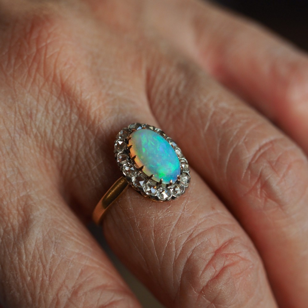 Victorian 18k gold cluster ring featuring an oval cabochon opal surrounded by a halo of rose-cut diamonds. View XVII
