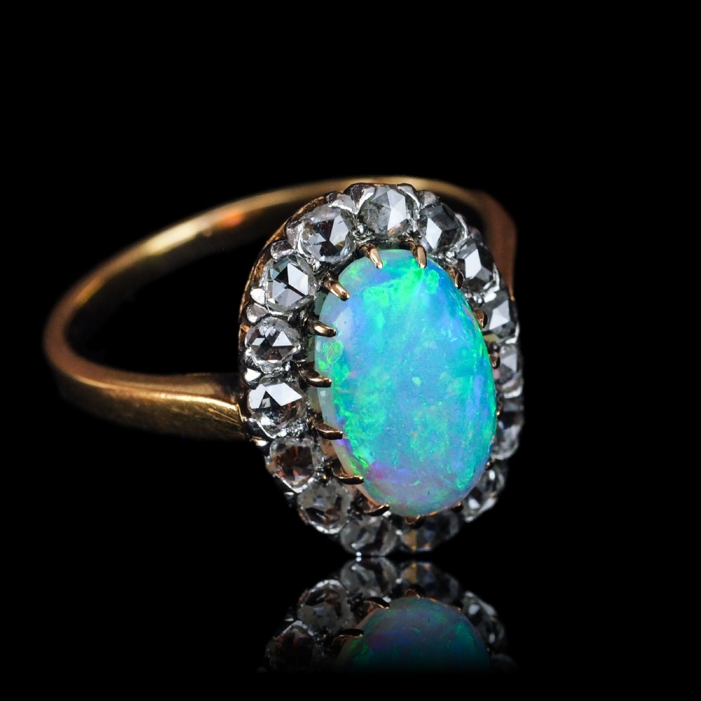 Victorian 18k gold cluster ring featuring an oval cabochon opal surrounded by a halo of rose-cut diamonds. View XVIII
