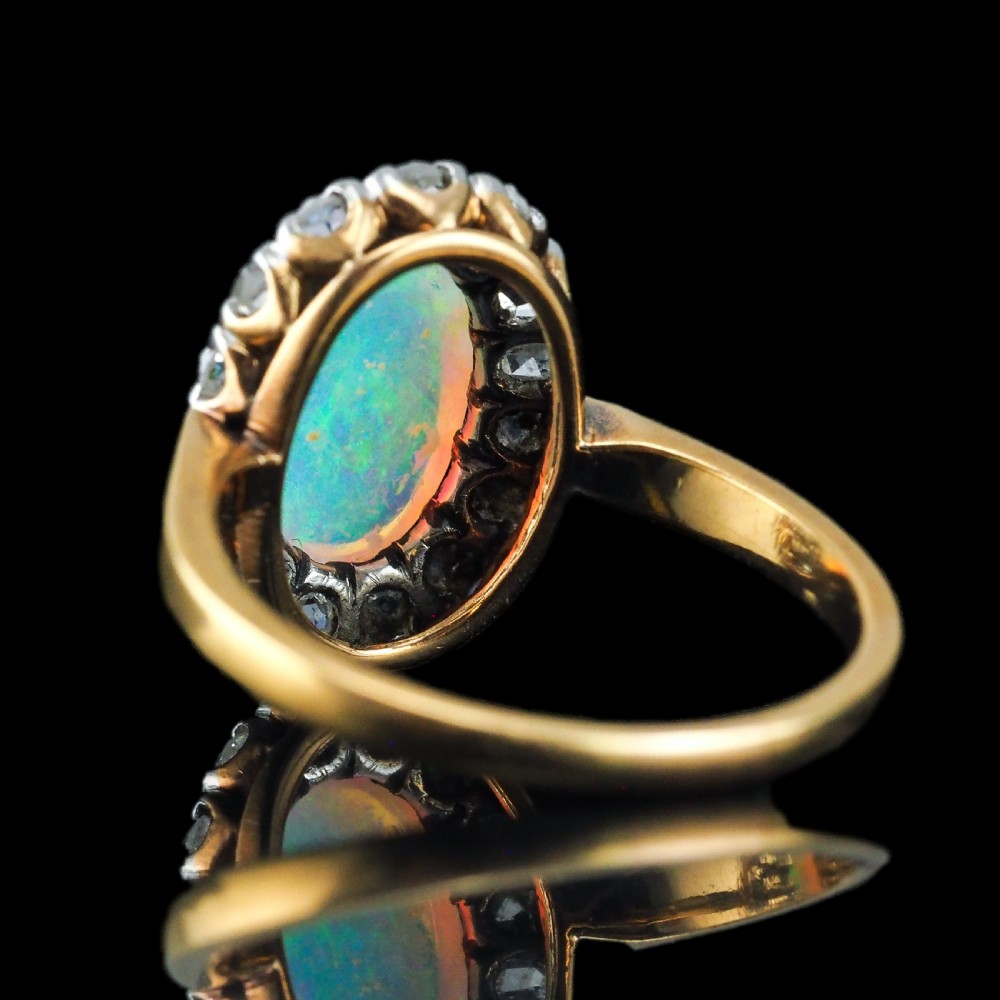 Victorian 18k gold cluster ring featuring an oval cabochon opal surrounded by a halo of rose-cut diamonds. View XIX