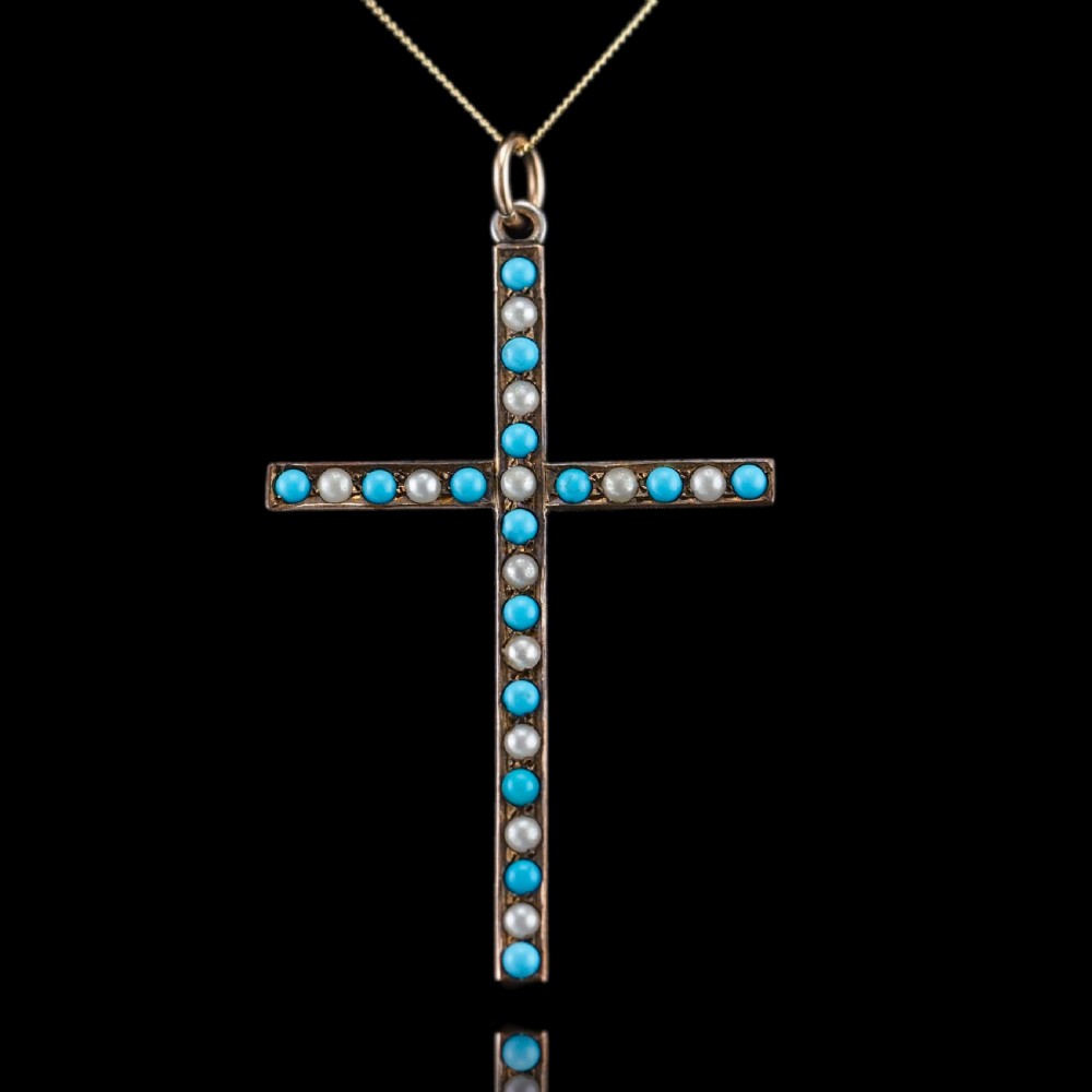 An antique 9ct gold cross pendant set with alternating blue turquoise cabochons and white seed pearls, suspended from a fine gold chain.