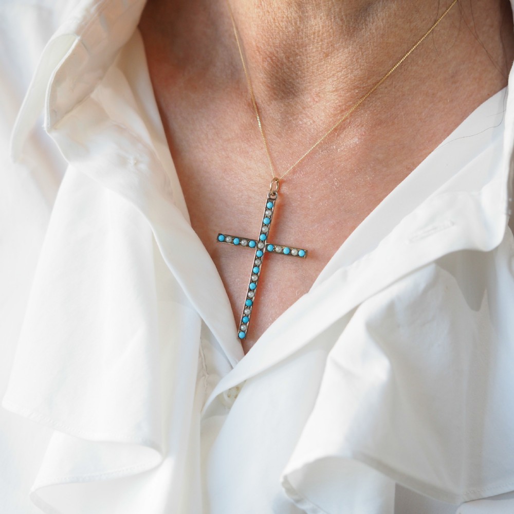 An antique 9ct gold cross pendant set with alternating blue turquoise cabochons and white seed pearls, suspended from a fine gold chain. View VI