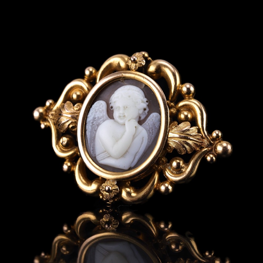 An oval Victorian shell cameo depicting a relief-carved cherub, mounted in an 18ct gold frame with scrollwork and leaf motifs. View II