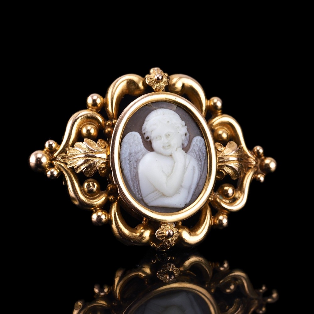 An oval Victorian shell cameo depicting a relief-carved cherub, mounted in an 18ct gold frame with scrollwork and leaf motifs. View III