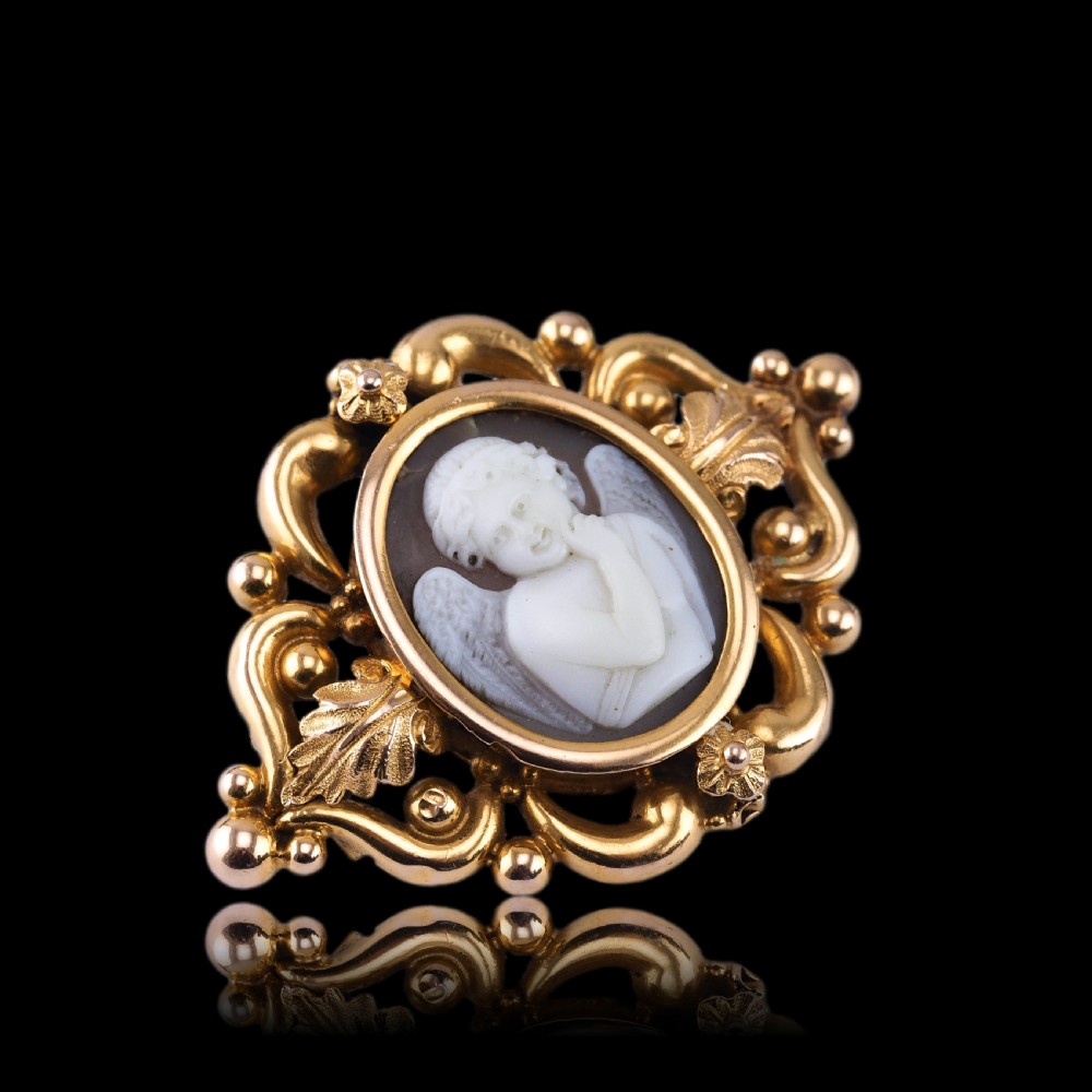 An oval Victorian shell cameo depicting a relief-carved cherub, mounted in an 18ct gold frame with scrollwork and leaf motifs. View IV