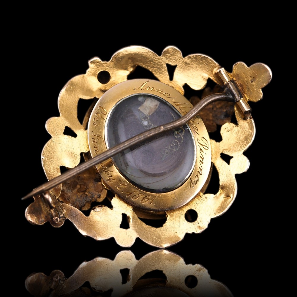 An oval Victorian shell cameo depicting a relief-carved cherub, mounted in an 18ct gold frame with scrollwork and leaf motifs. View XIII