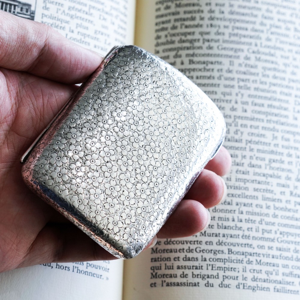 An antique Victorian sterling silver cigarette case decorated with an overall engraved floral pattern and a central oval cartouche containing a heraldic crest. View III