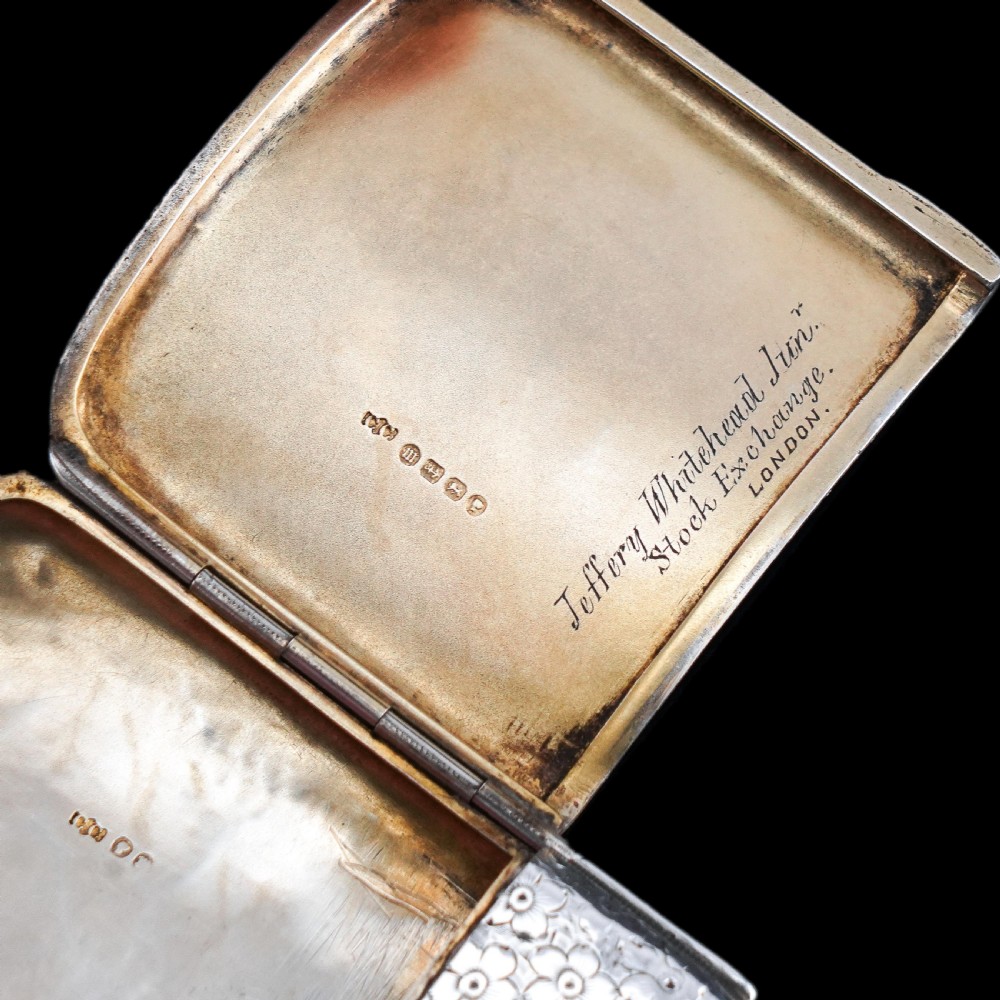 An antique Victorian sterling silver cigarette case decorated with an overall engraved floral pattern and a central oval cartouche containing a heraldic crest. View XI