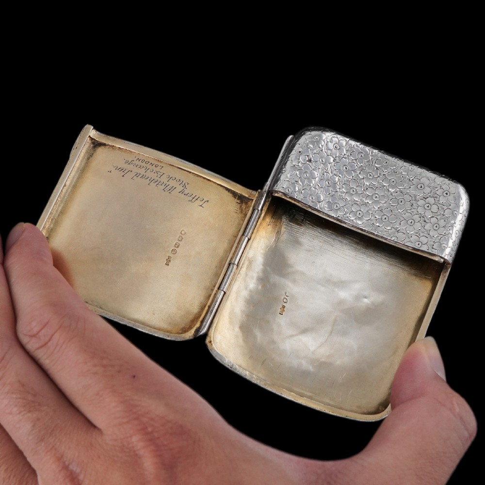 An antique Victorian sterling silver cigarette case decorated with an overall engraved floral pattern and a central oval cartouche containing a heraldic crest. View XII