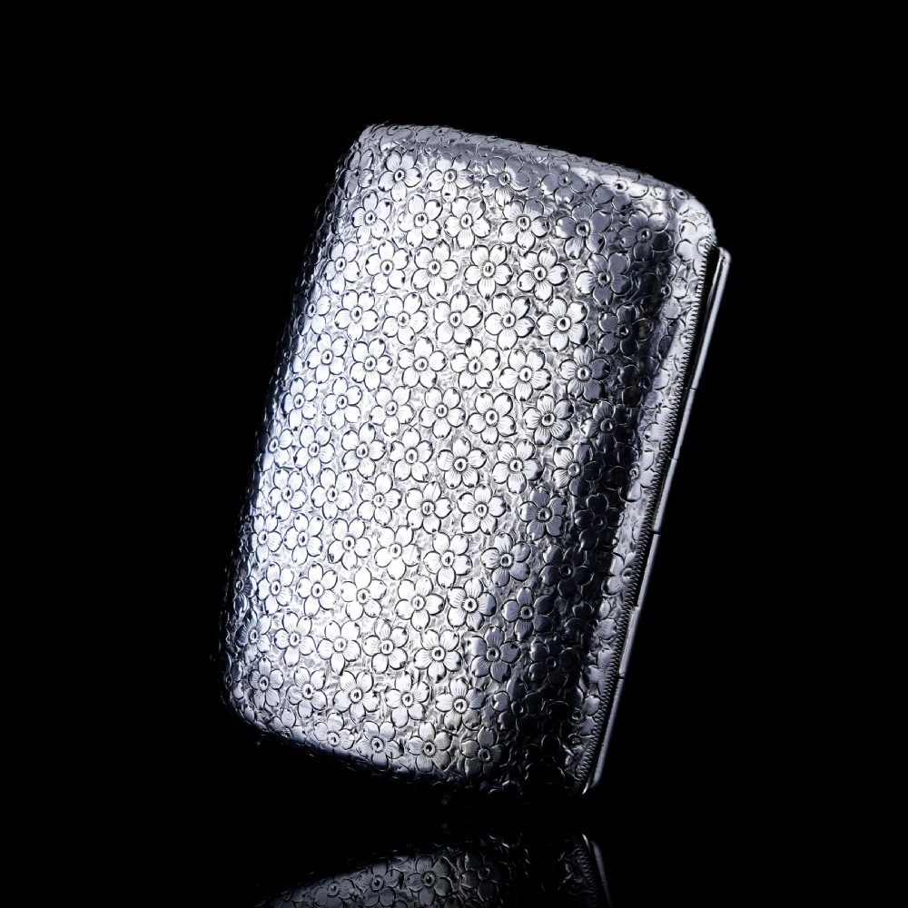 An antique Victorian sterling silver cigarette case decorated with an overall engraved floral pattern and a central oval cartouche containing a heraldic crest. View XIV