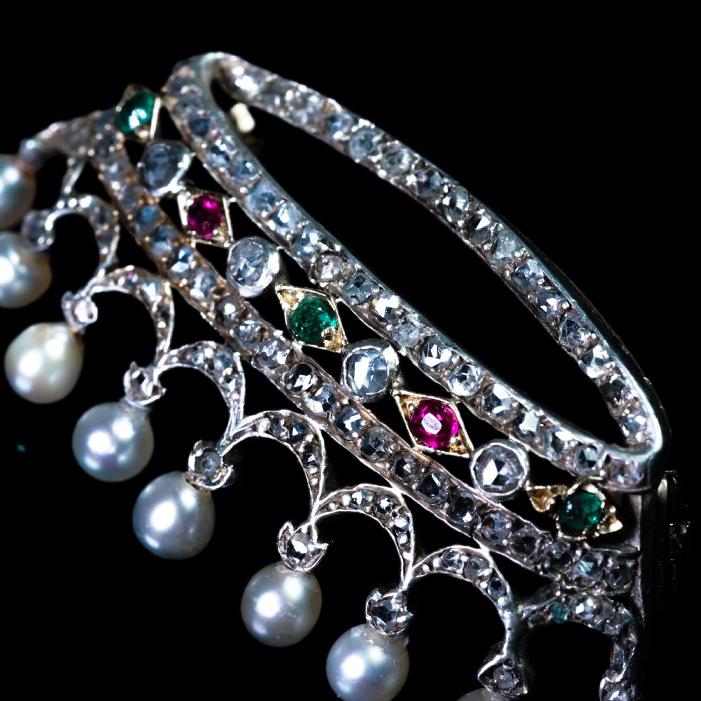 An antique French coronet brooch crafted in 18K gold and silver, encrusted with diamonds, rubies, emeralds, and topped with nine pearls. View XIV