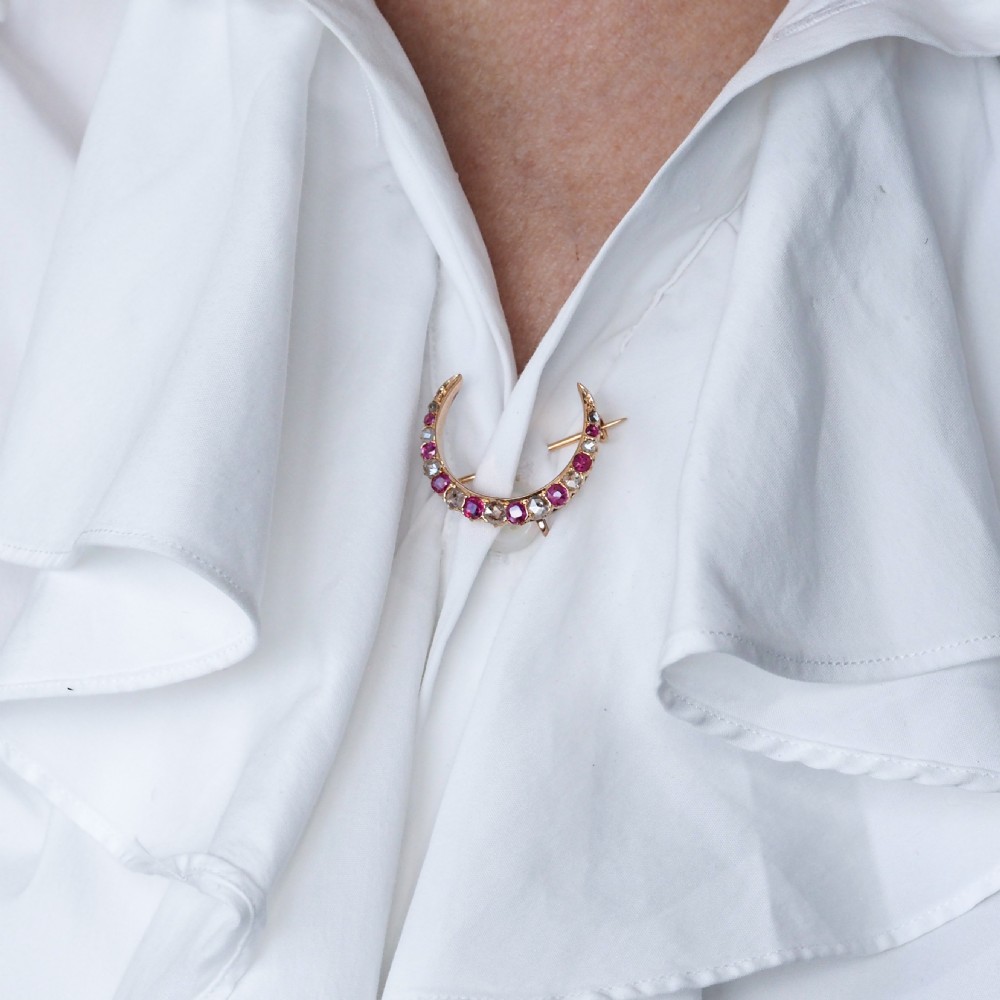 An 18K gold Victorian crescent moon brooch set with alternating cushion-cut rubies and old-cut diamonds. View X