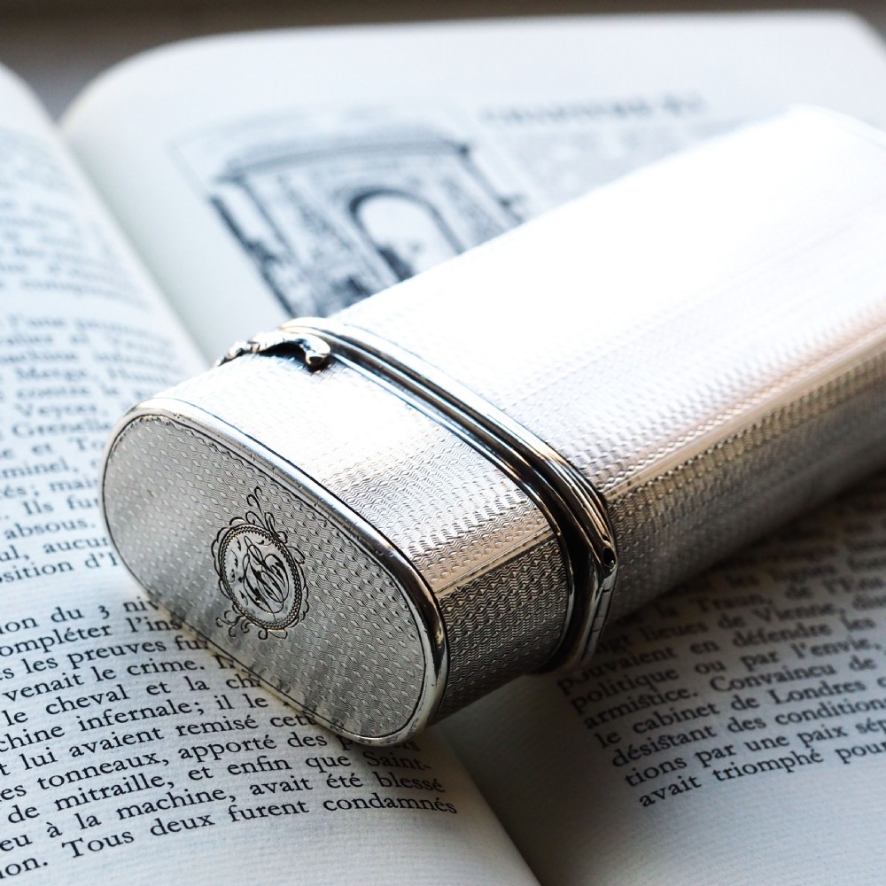 An antique engine-turned solid silver cigar case featuring floral relief thumbpiece detailing and an engraved cartouche on the end. View II