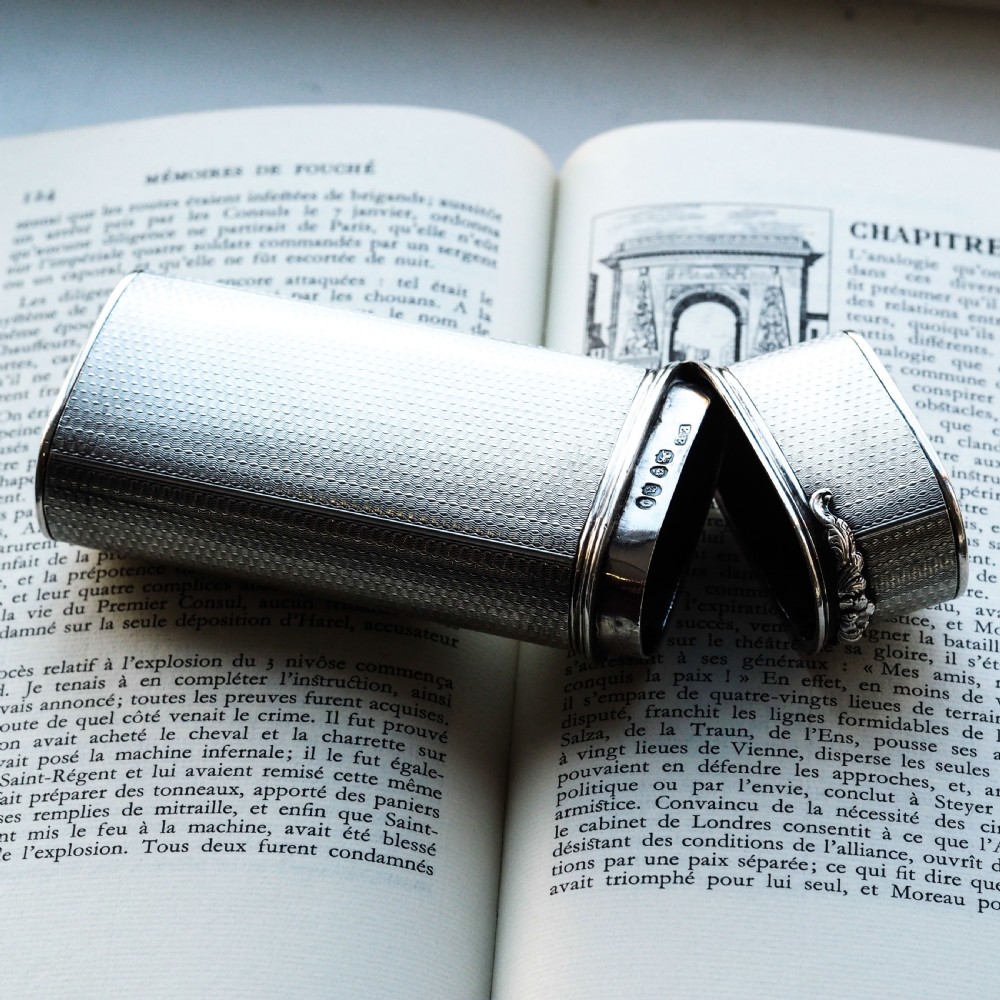An antique engine-turned solid silver cigar case featuring floral relief thumbpiece detailing and an engraved cartouche on the end. View IV