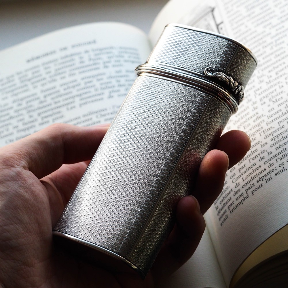 An antique engine-turned solid silver cigar case featuring floral relief thumbpiece detailing and an engraved cartouche on the end. View IX