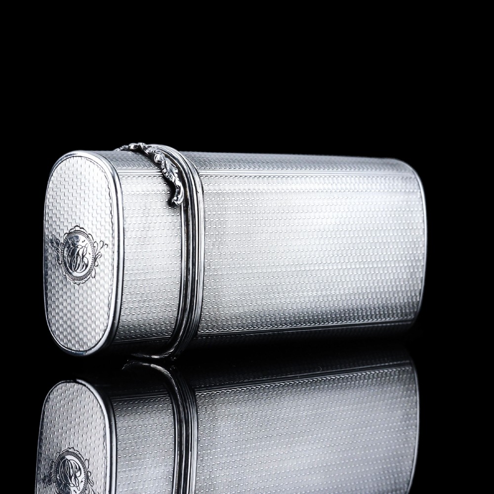 An antique engine-turned solid silver cigar case featuring floral relief thumbpiece detailing and an engraved cartouche on the end. View X