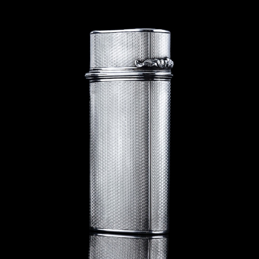An antique engine-turned solid silver cigar case featuring floral relief thumbpiece detailing and an engraved cartouche on the end. View XII