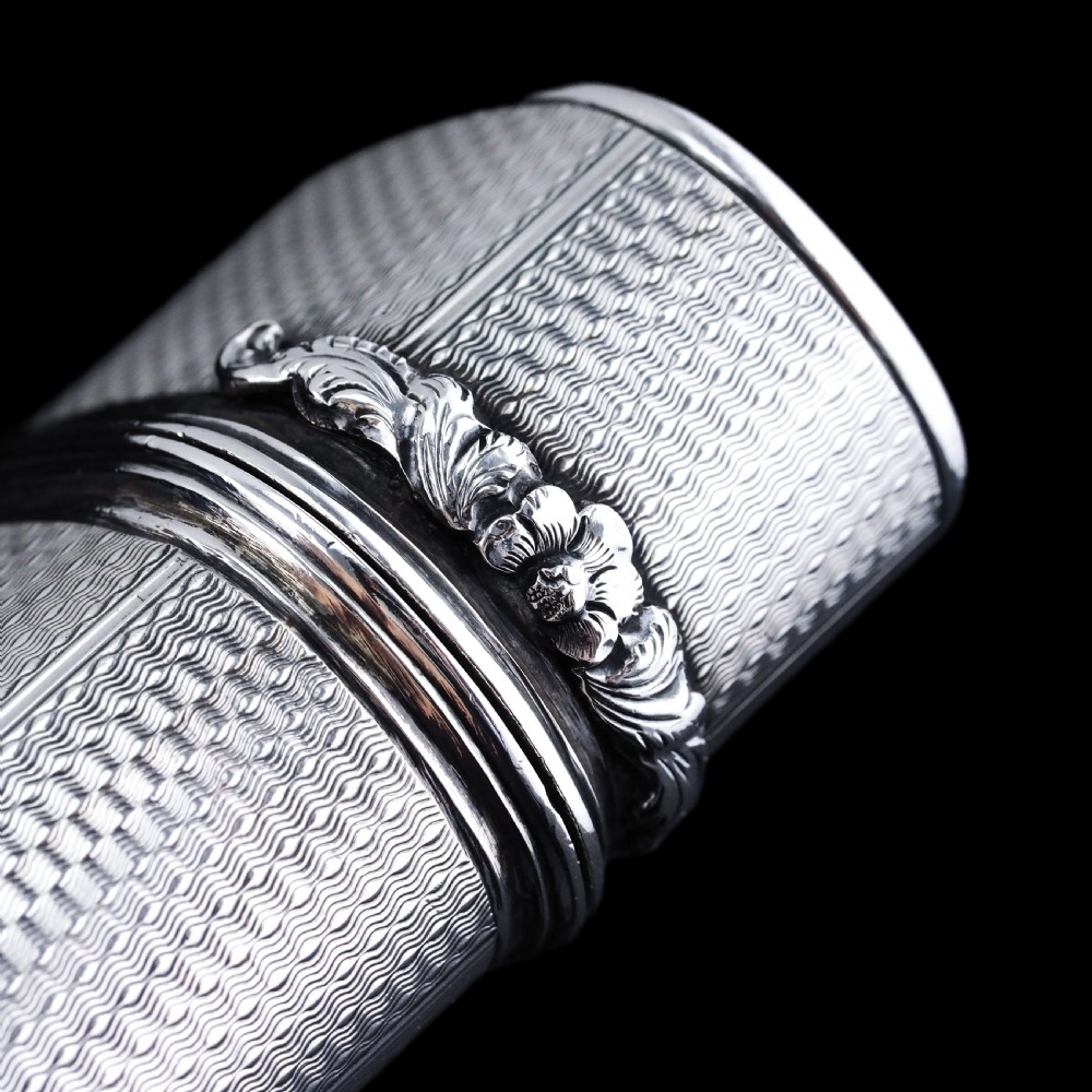 An antique engine-turned solid silver cigar case featuring floral relief thumbpiece detailing and an engraved cartouche on the end. View XIV