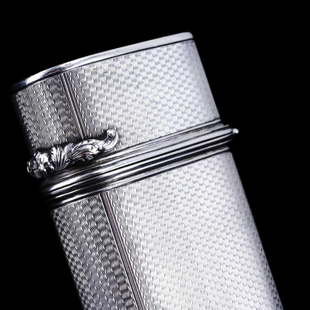 An antique engine-turned solid silver cigar case featuring floral relief thumbpiece detailing and an engraved cartouche on the end. View XX