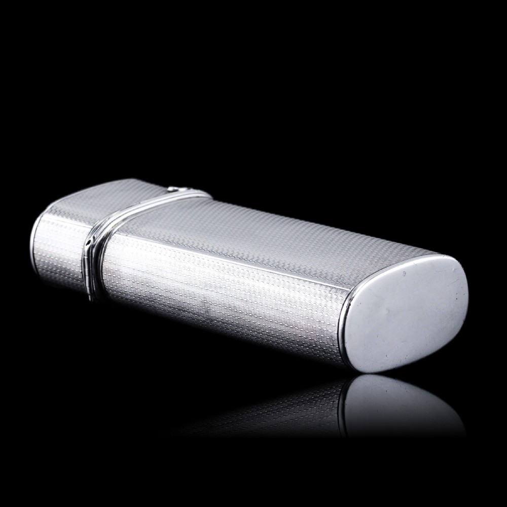 An antique engine-turned solid silver cigar case featuring floral relief thumbpiece detailing and an engraved cartouche on the end. View XXII