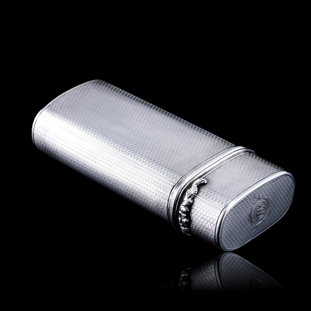 An antique engine-turned solid silver cigar case featuring floral relief thumbpiece detailing and an engraved cartouche on the end. View XXIII
