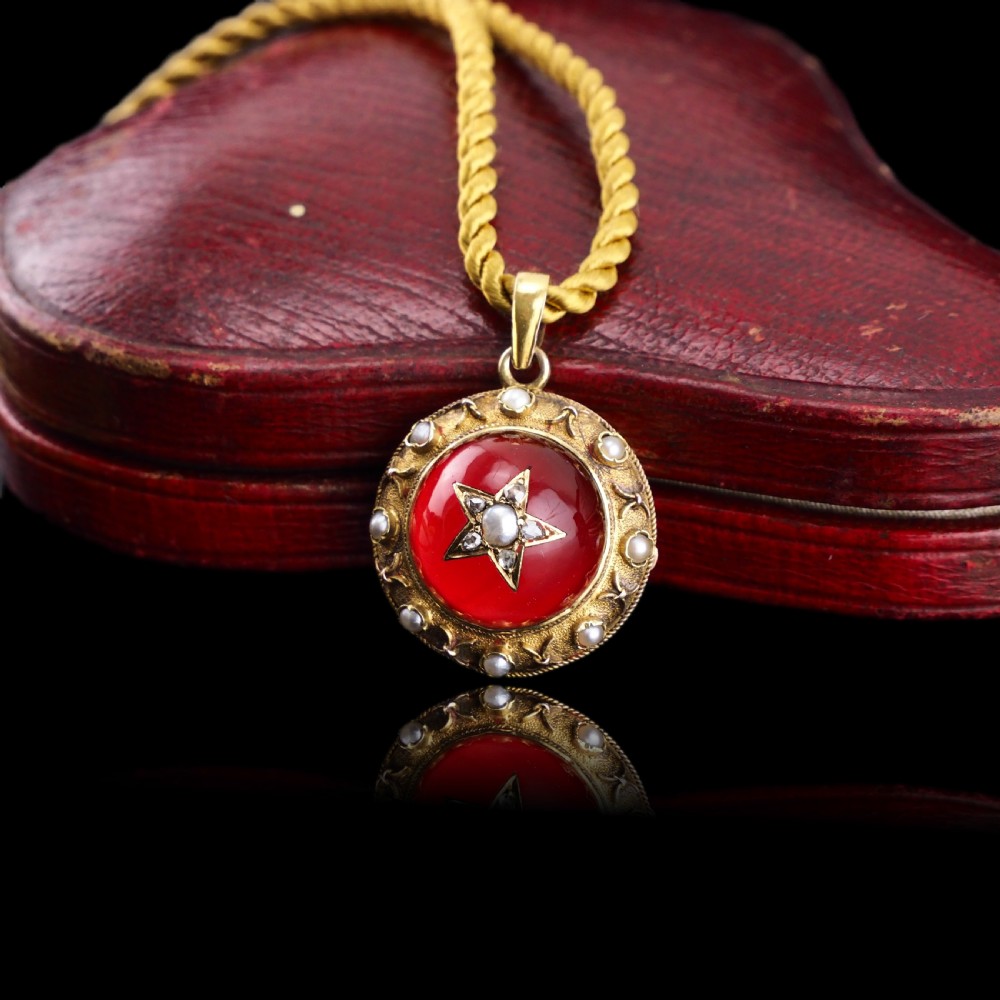 Victorian 15ct gold circular pendant featuring a red rock crystal cabochon accented with a diamond and pearl star motif and surrounded by a pearl border. View VII