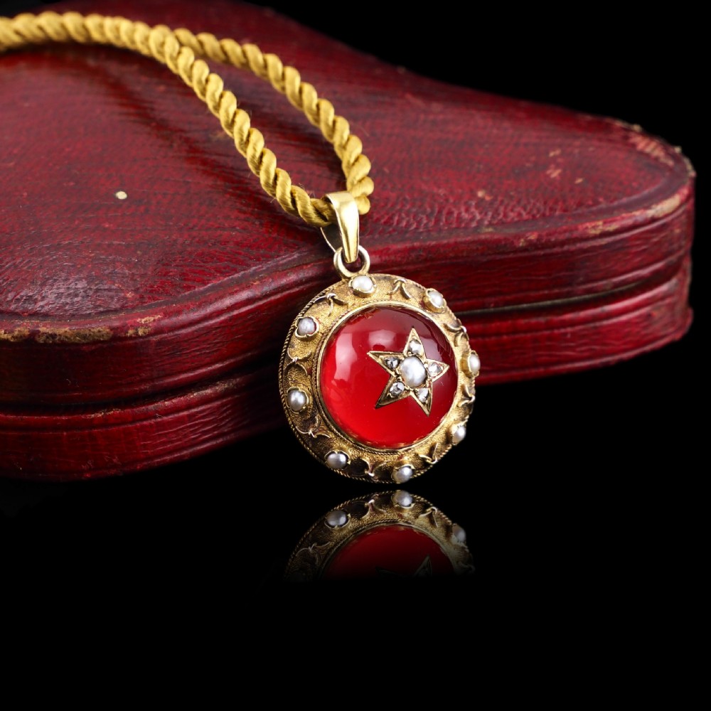 Victorian 15ct gold circular pendant featuring a red rock crystal cabochon accented with a diamond and pearl star motif and surrounded by a pearl border. View VIII