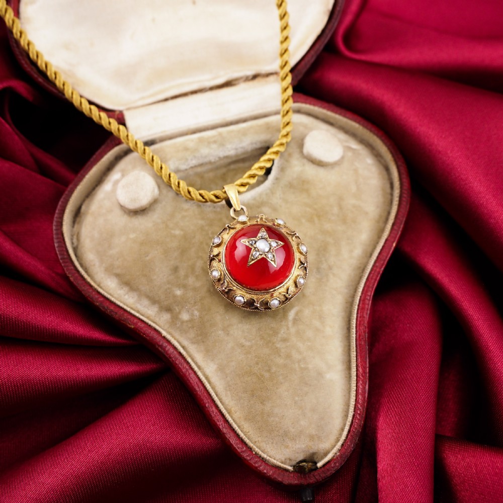 Victorian 15ct gold circular pendant featuring a red rock crystal cabochon accented with a diamond and pearl star motif and surrounded by a pearl border. View XII
