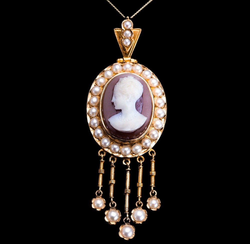 A Victorian 14K gold oval pendant featuring a carved white shell cameo profile against a brown background, framed by a border of seed pearls with articulated pearl drops. View II