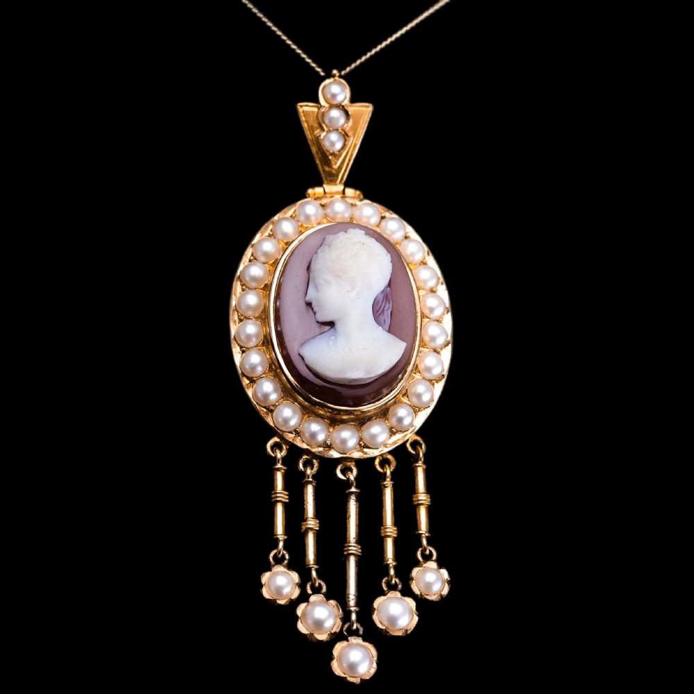 A Victorian 14K gold oval pendant featuring a carved white shell cameo profile against a brown background, framed by a border of seed pearls with articulated pearl drops. View III