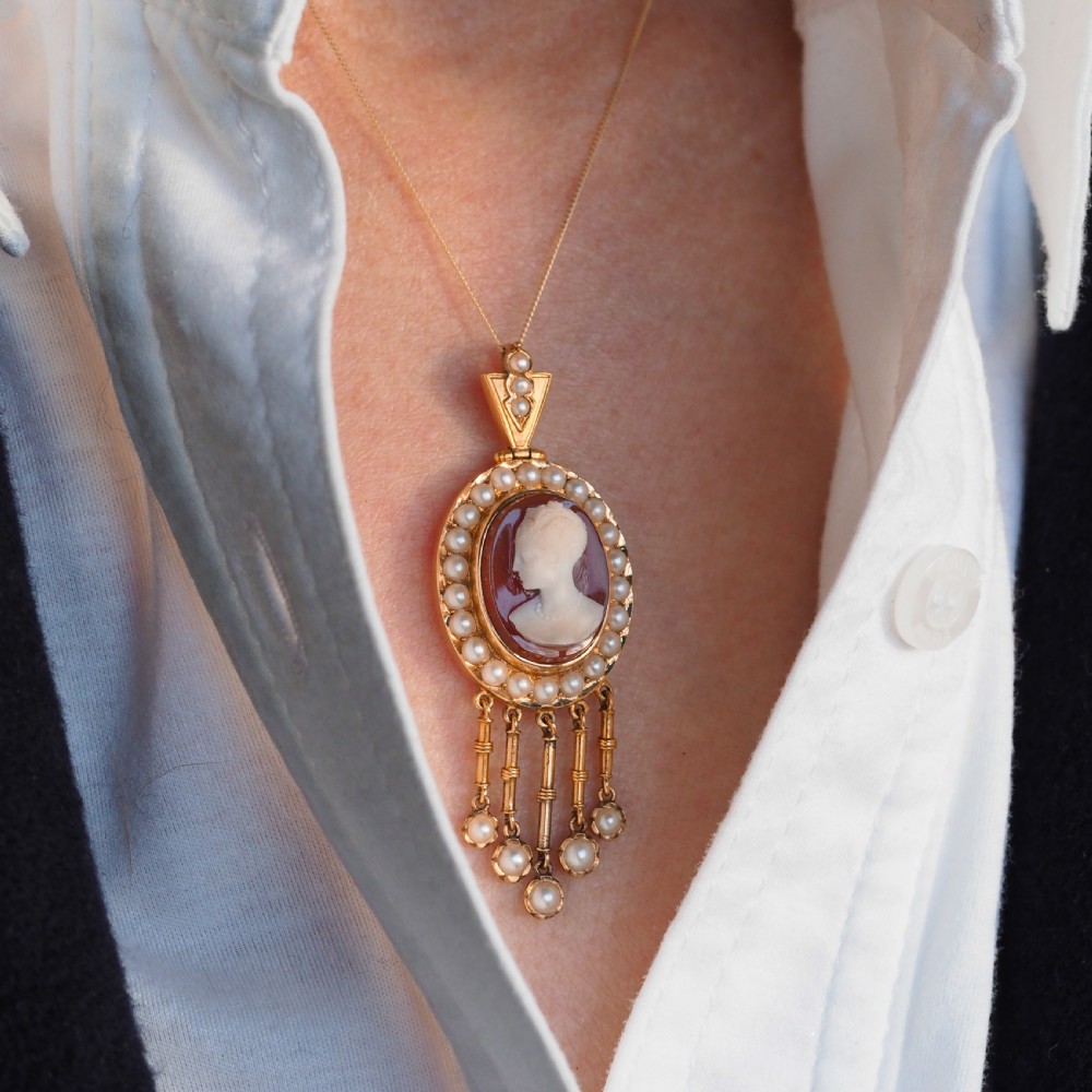 A Victorian 14K gold oval pendant featuring a carved white shell cameo profile against a brown background, framed by a border of seed pearls with articulated pearl drops. View VIII