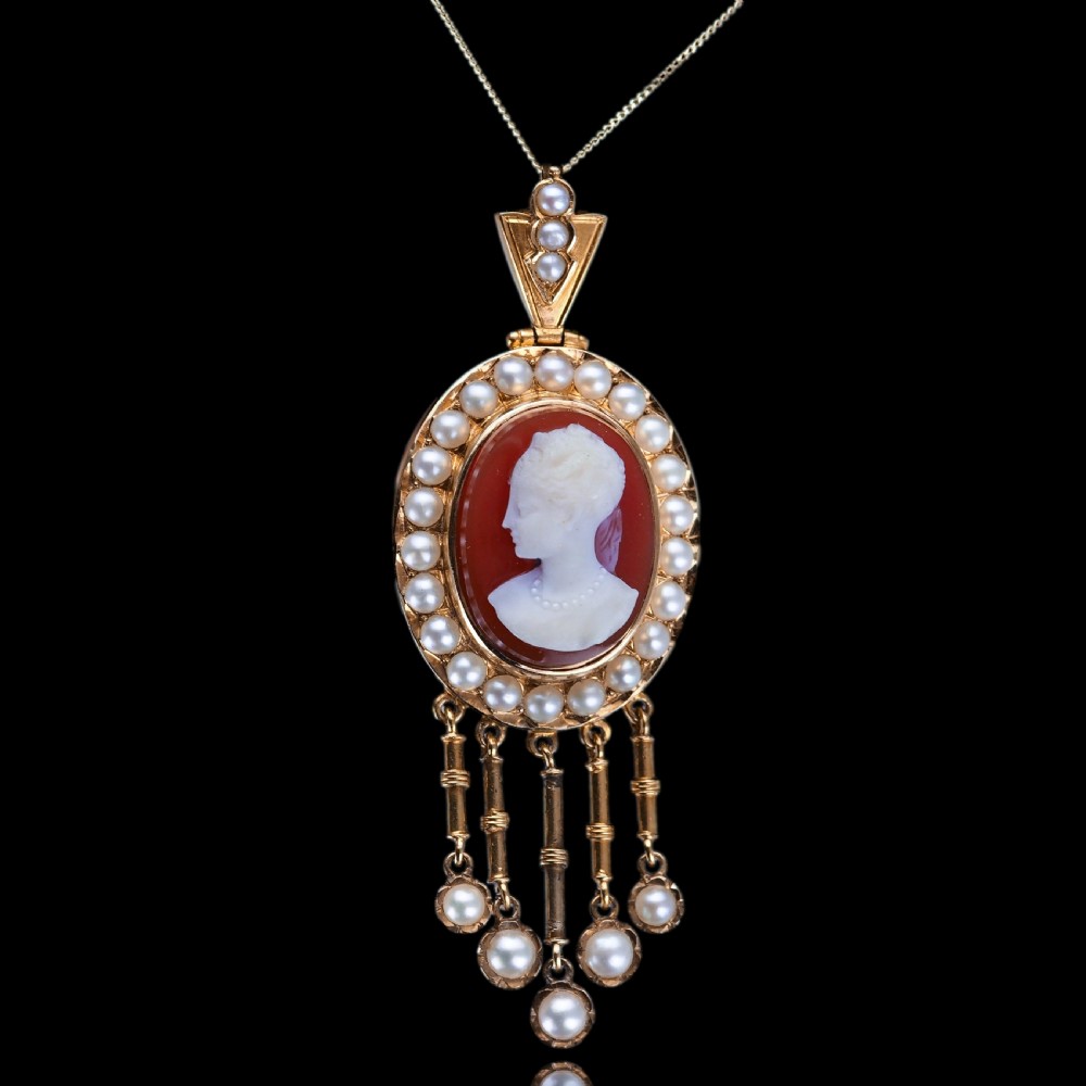 A Victorian 14K gold oval pendant featuring a carved white shell cameo profile against a brown background, framed by a border of seed pearls with articulated pearl drops. View XIII
