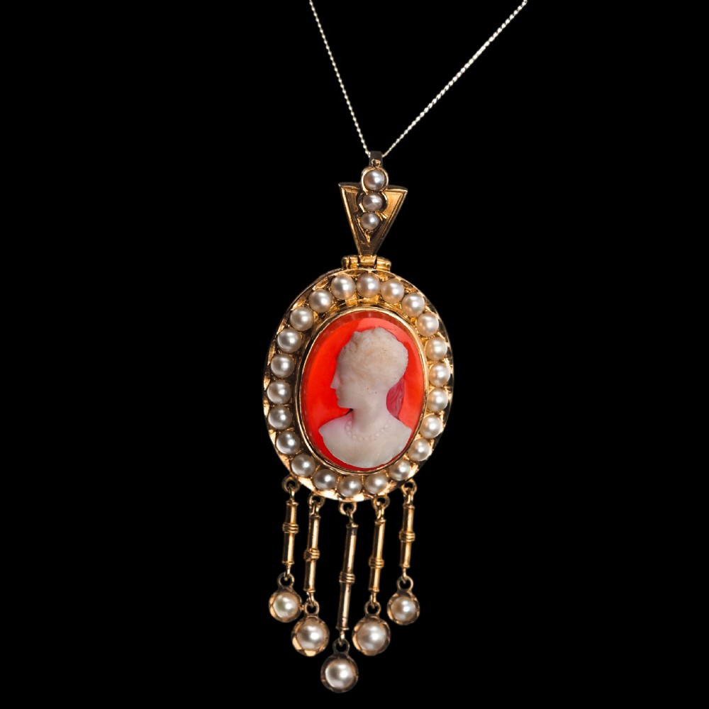 A Victorian 14K gold oval pendant featuring a carved white shell cameo profile against a brown background, framed by a border of seed pearls with articulated pearl drops. View XIV