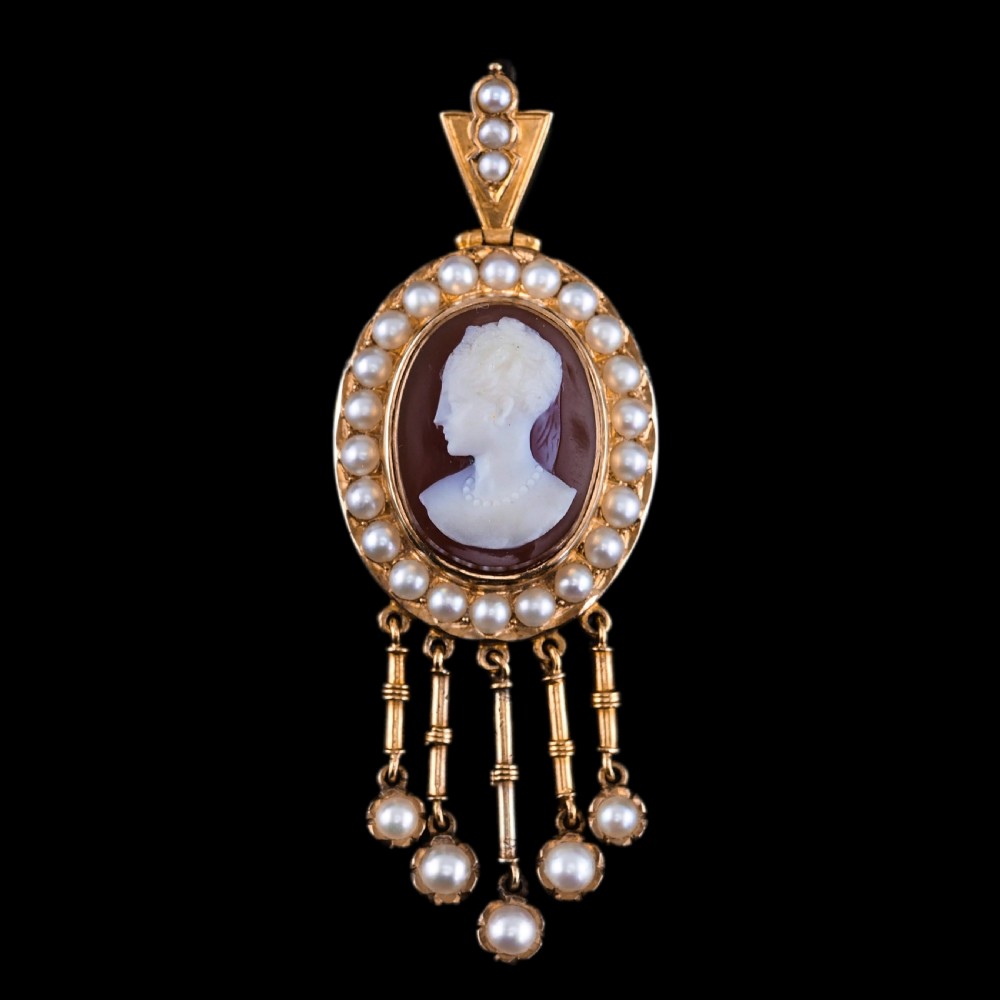 A Victorian 14K gold oval pendant featuring a carved white shell cameo profile against a brown background, framed by a border of seed pearls with articulated pearl drops. View XVIII