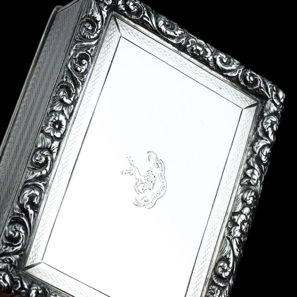 A rectangular sterling silver table snuff box featuring a chased floral border, an engine-turned cover with a central engraved crest, and straight sides. View XI