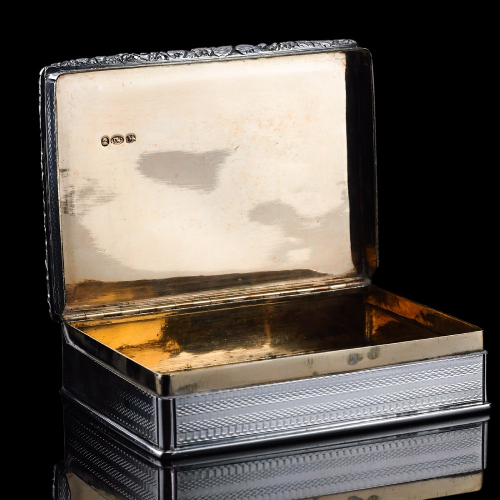 A rectangular sterling silver table snuff box featuring a chased floral border, an engine-turned cover with a central engraved crest, and straight sides. View XIII