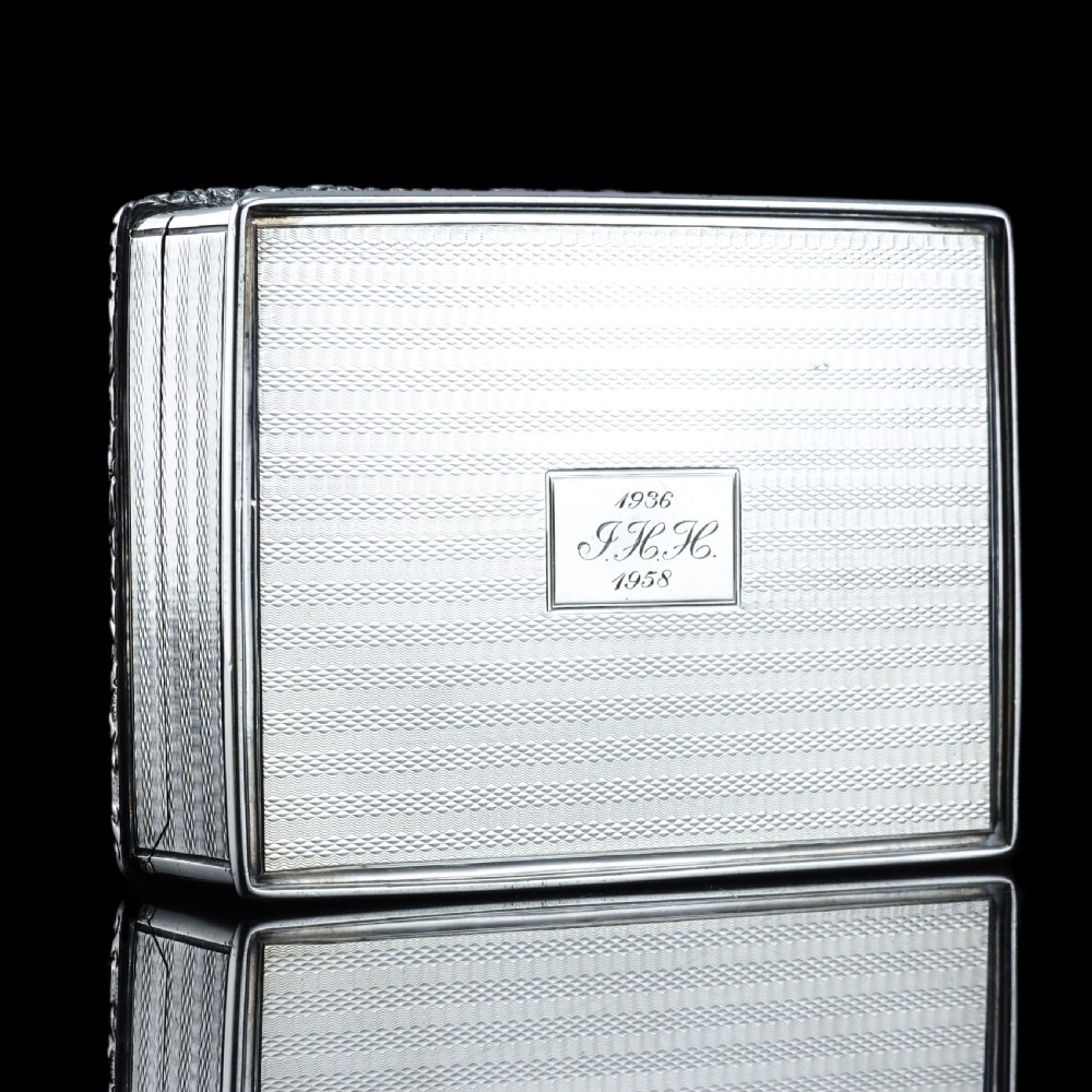 A rectangular sterling silver table snuff box featuring a chased floral border, an engine-turned cover with a central engraved crest, and straight sides. View XV