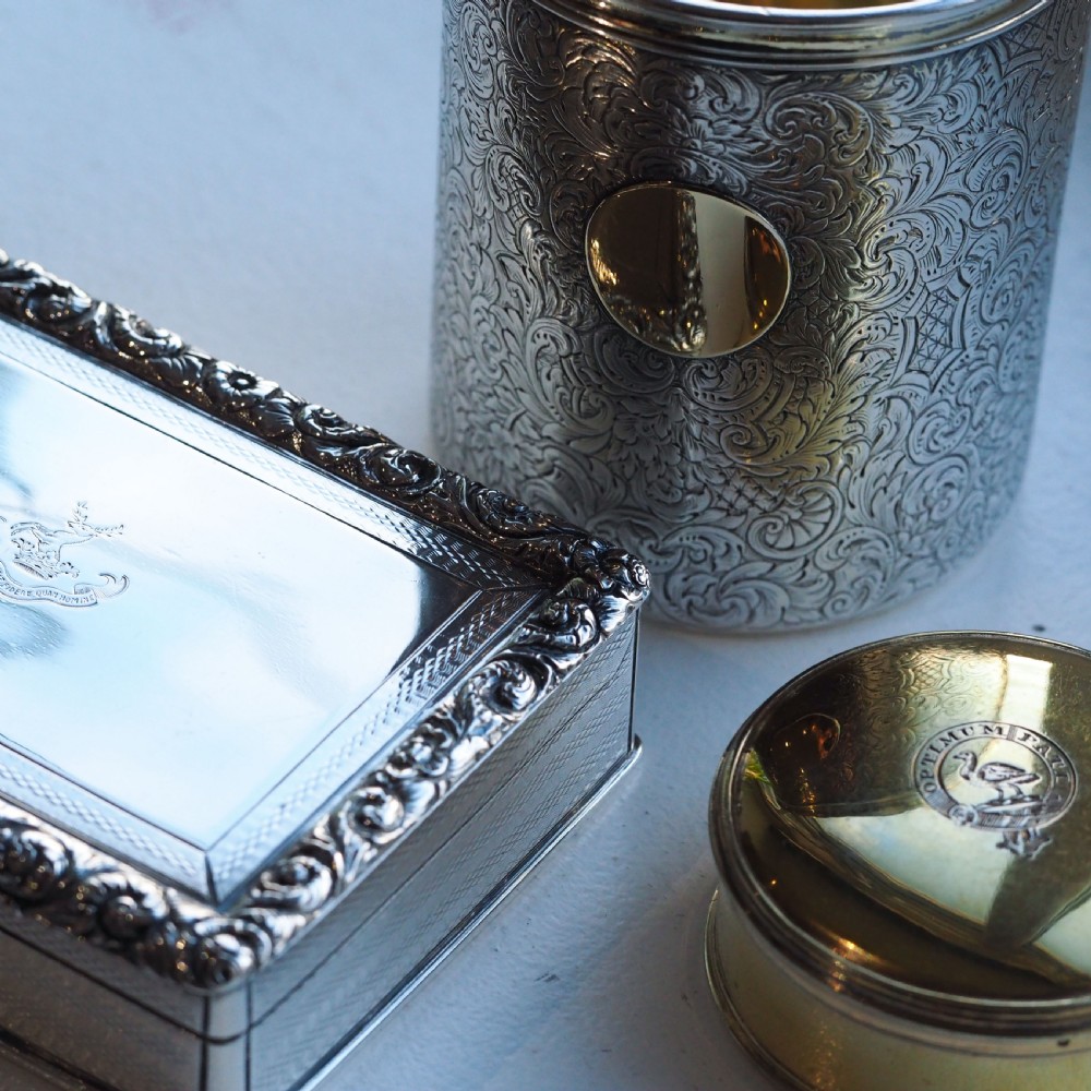 A rectangular sterling silver table snuff box featuring a chased floral border, an engine-turned cover with a central engraved crest, and straight sides. View XX
