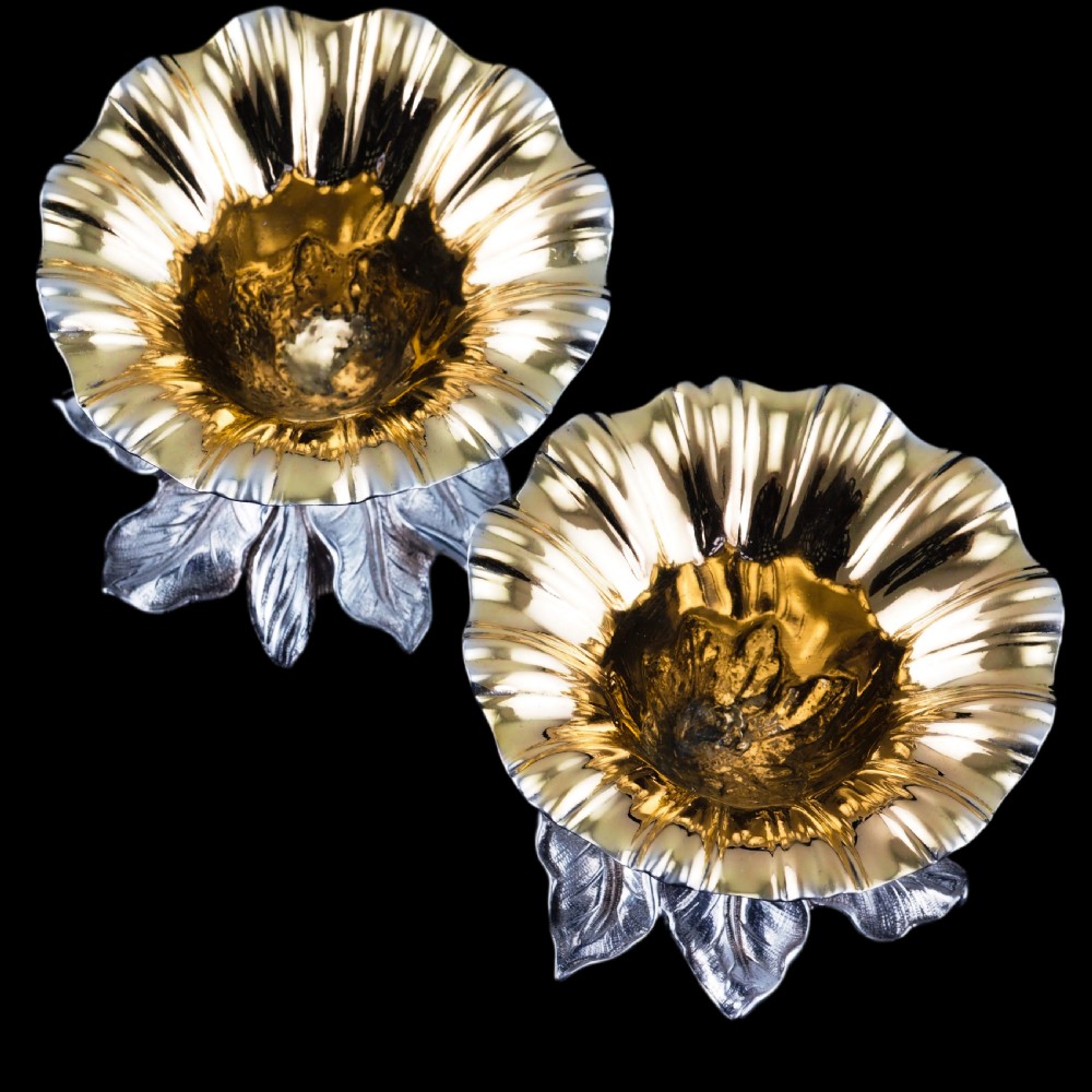 A pair of William IV sterling silver salt cellars designed as open flower heads with gilded interiors resting on naturalistic leaf bases. View IV