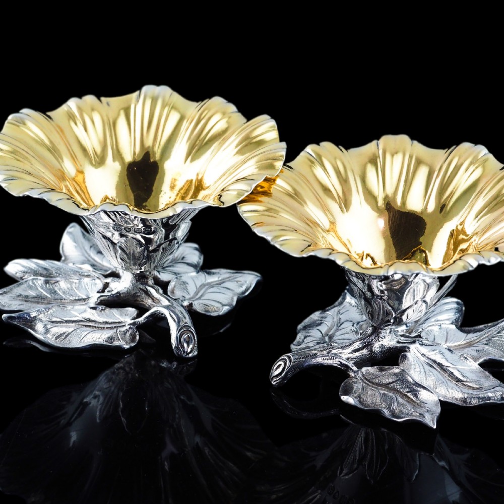 A pair of William IV sterling silver salt cellars designed as open flower heads with gilded interiors resting on naturalistic leaf bases. View V
