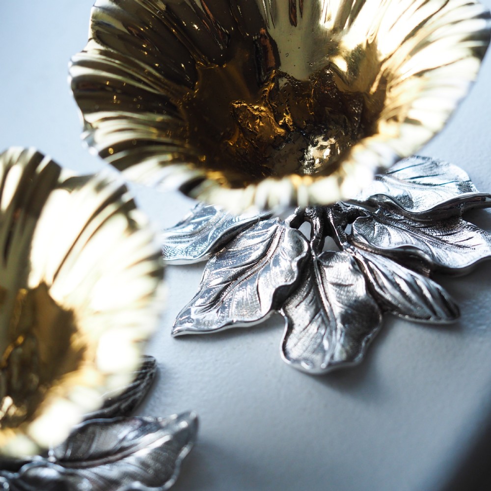A pair of William IV sterling silver salt cellars designed as open flower heads with gilded interiors resting on naturalistic leaf bases. View XVIII