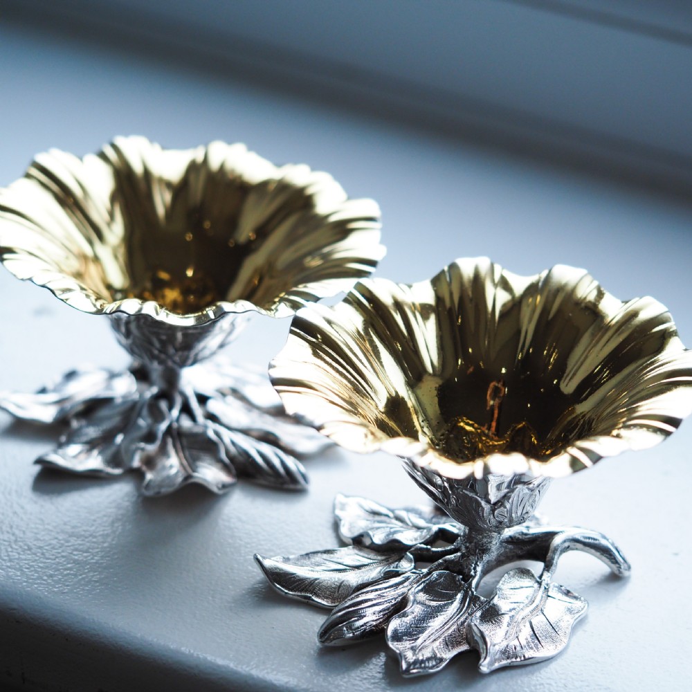 A pair of William IV sterling silver salt cellars designed as open flower heads with gilded interiors resting on naturalistic leaf bases. View XIX